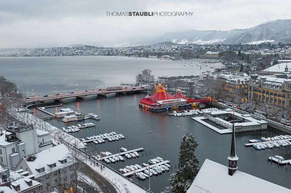 trüber verschneiter Wintertag über Zürich mit Blick auf das rote Zirkuszelt auf dem Bauschänzli