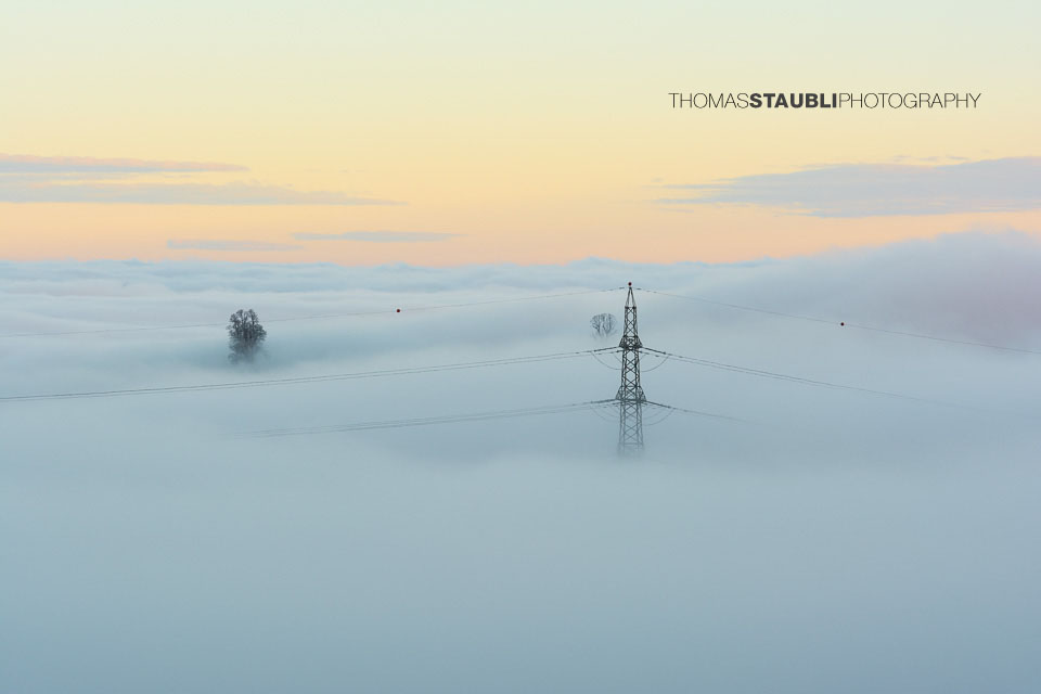 Strommast ragt aus dem Nebelmeer