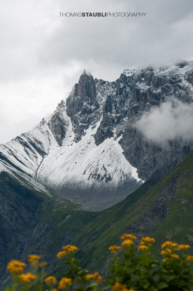 Wolkenverhangenes und weiss gezuckertes Zwölfihorn der Glarner Alpen