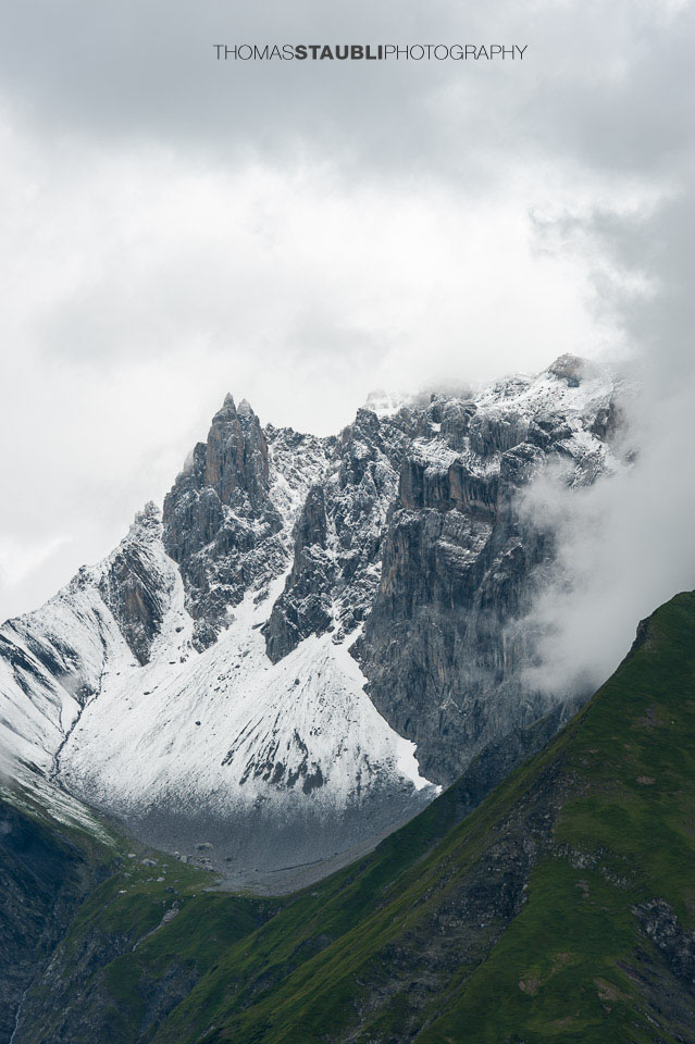 Wolkenverhangenes und weiss gezuckertes Zwölfihorn der Glarner Alpen