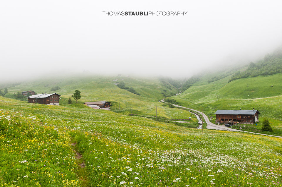 Nebel über den Bauernhöfen und Blumenwiesen von St. Antönien und Partnun