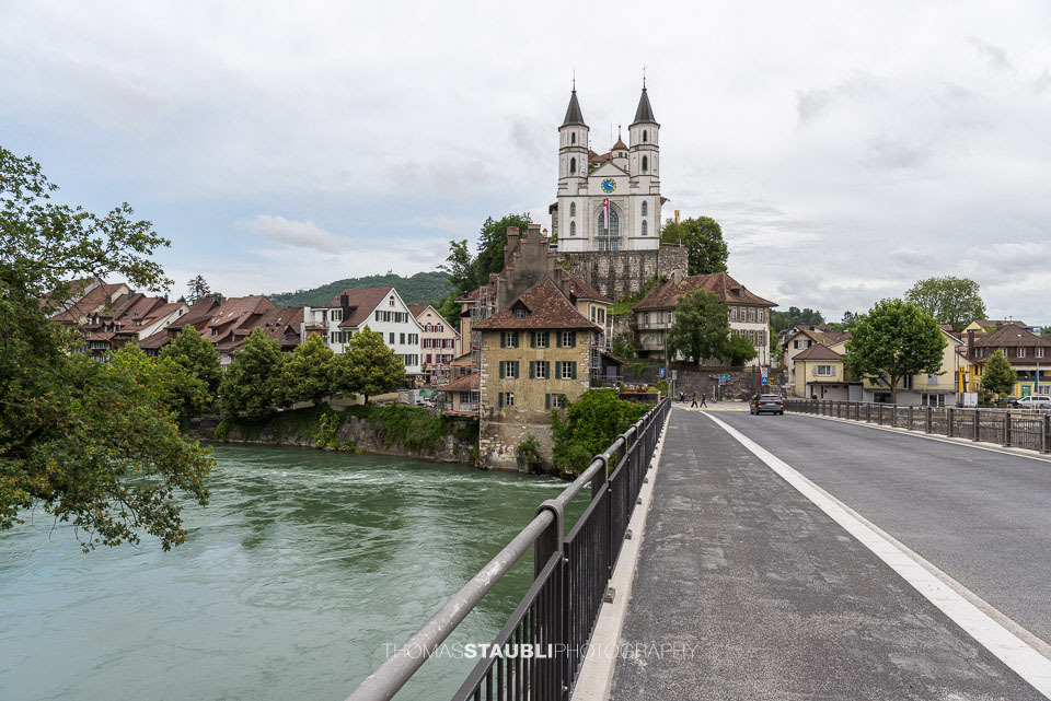 Die reformierte Kirche von Aarburg thront auf einem Felssporn über dem Fluss Aare. Im Vordergrund ist die Brücke ins historische Städtchen zu sehen.