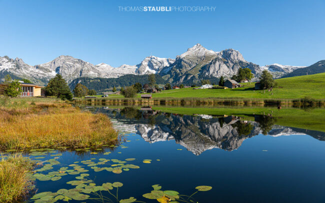 der verschneite Alpstein spiegelt sich im herbstlichen Schwendisee