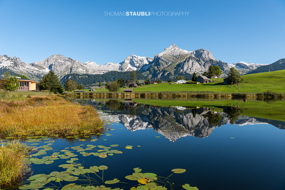 der verschneite Alpstein spiegelt sich im herbstlichen Schwendisee