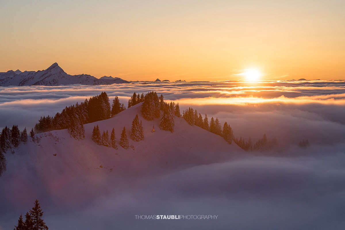 Sonnenuntergang über verschneiter Landschaft mit Nebelmeer