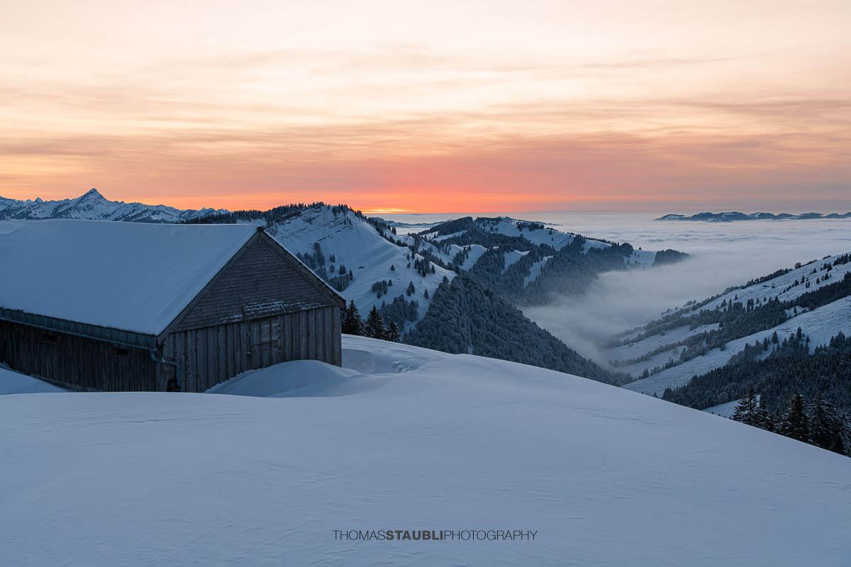 Verschneite Berghütten in den Schweizer Alpen bei Sonnenuntergang mit beeindruckender Bergkulisse