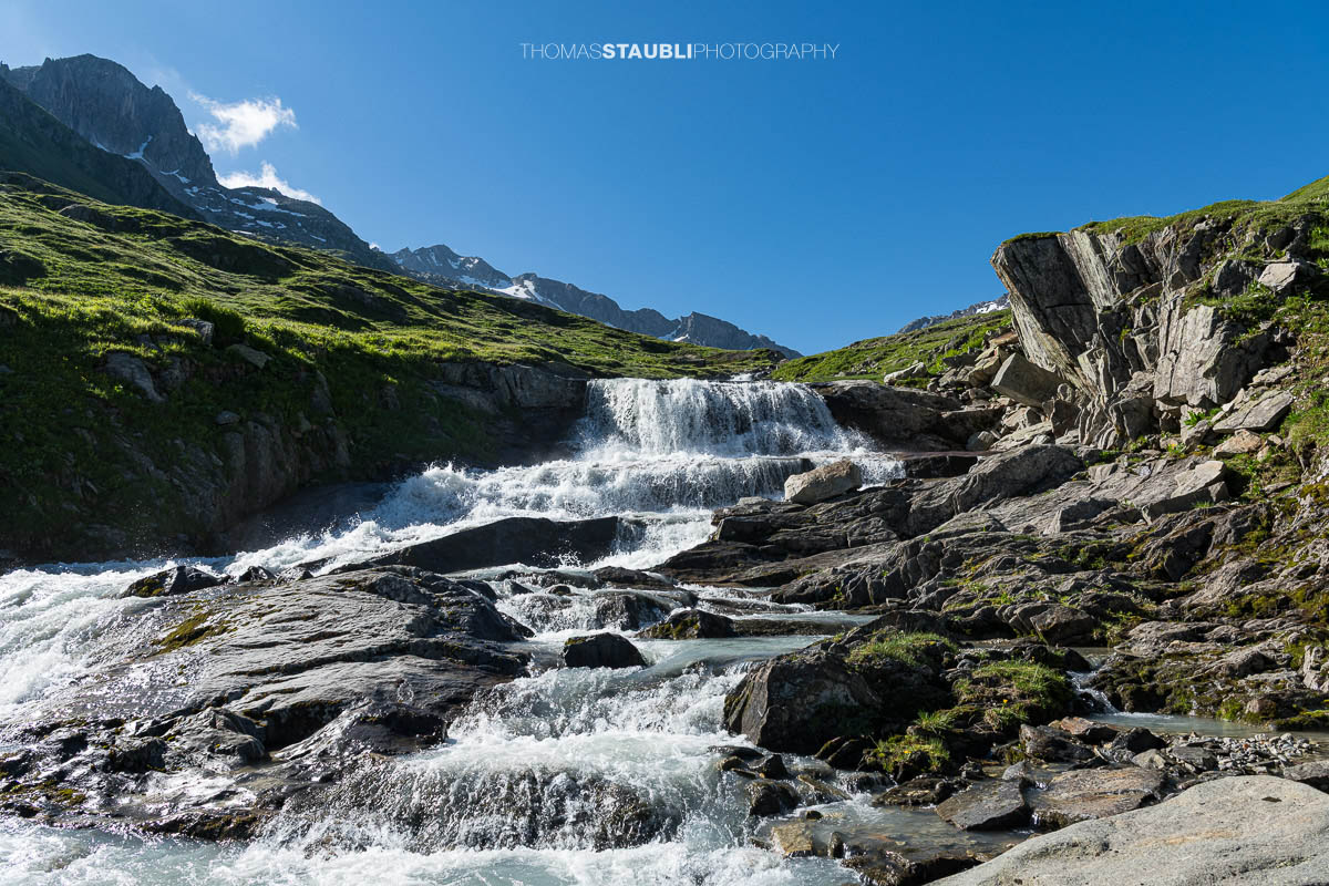 Die Witenwasserenreuss rauscht über Felsstufen durch das grüne Witenwasserental im Kanton Uri.