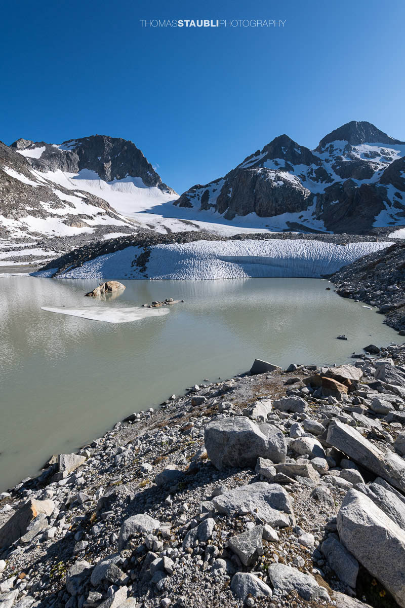 Gletschersee des Witenwasserengletschers, im Hintergrund vor blauem Himmel der Hüenerstock und Witenwasserenstock.