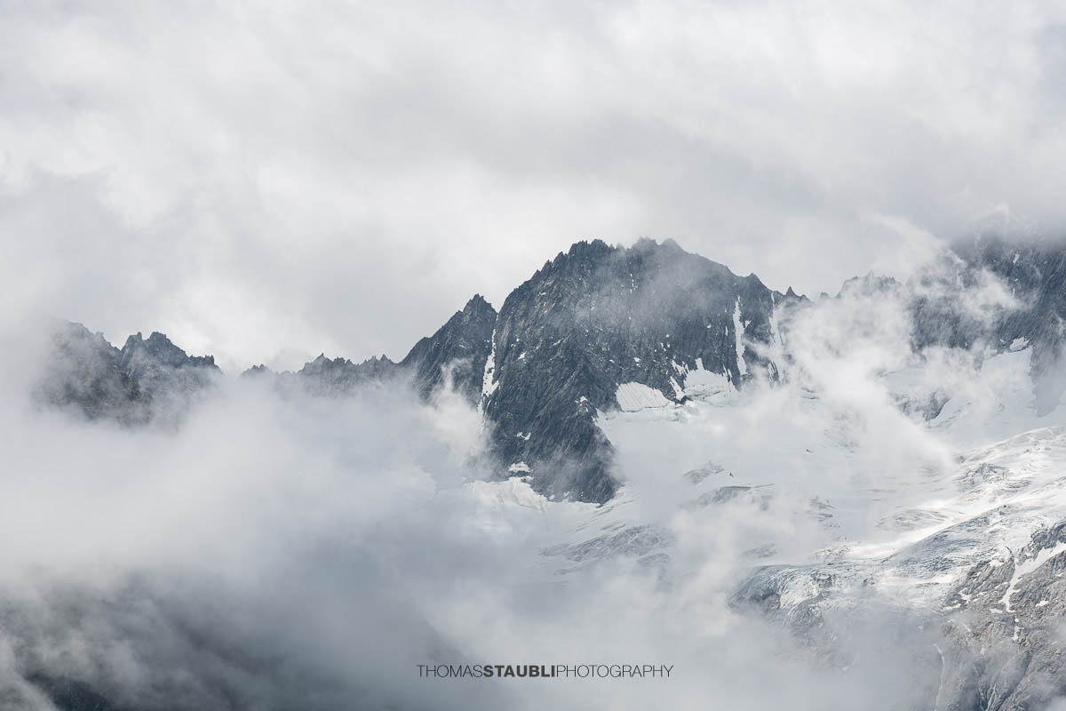 Dramatischer Blick von der Göscheneralp im Kanton Uri zum wolkenverhangenen Winterbergmassiv mit Gletscherfeldern und markanten Felszacken.