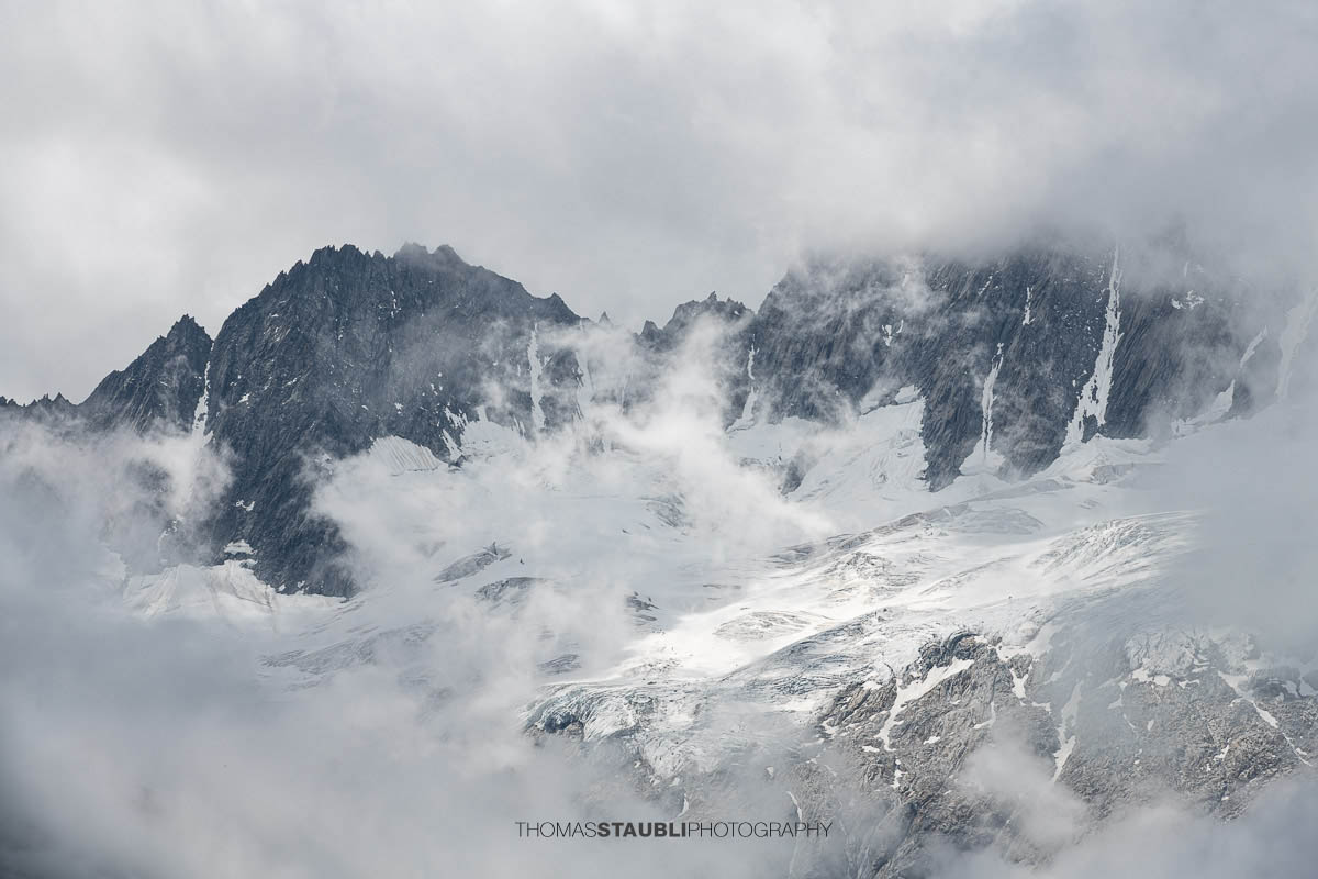 Dramatischer Blick von der Göscheneralp im Kanton Uri zum wolkenverhangenen Winterbergmassiv mit Gletscherfeldern und markanten Felszacken.