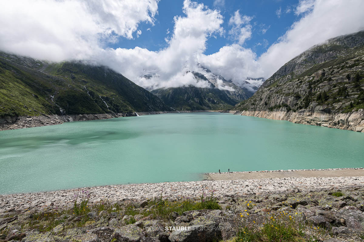 Blick vom Göscheneralpsee im Kanton Uri zum wolkenverhangenen Winterbergmassiv mit Gletscher und steilen Felsflanken.