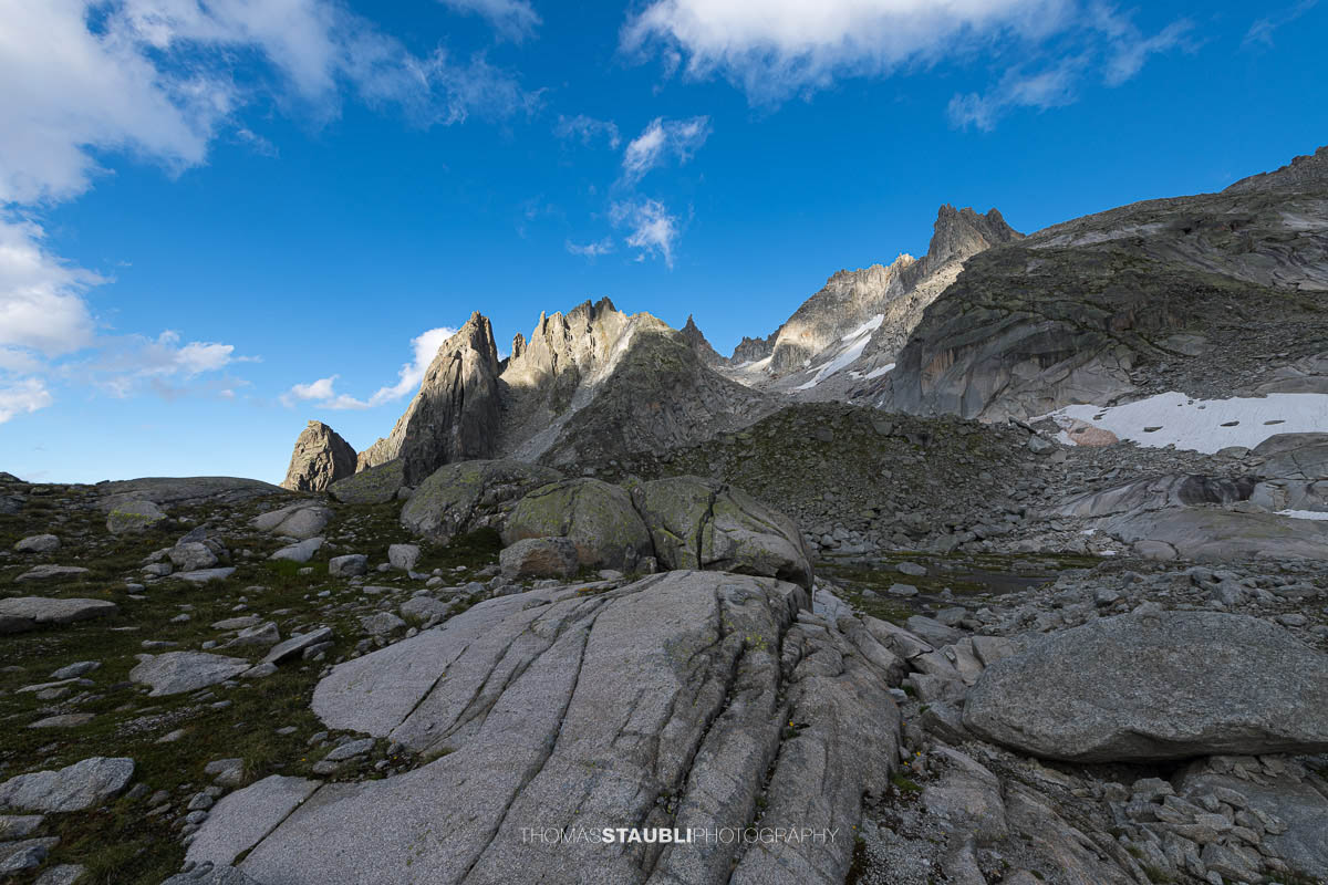 Felsige Landschaft der Älprigen mit Blick auf Mittagstock, Feldschijen und Blauberg unter blauem Himmel mit Wolken.