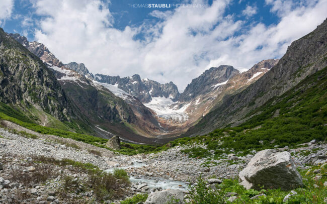 Blick durch das Chelenalptal im Kanton Uri, wo der Chelenreuss zwischen Geröllfeldern und alpiner Vegetation talwärts fliesst, während im Hintergrund der Chelengletscher unterhalb des Winterbergmassivs liegt.