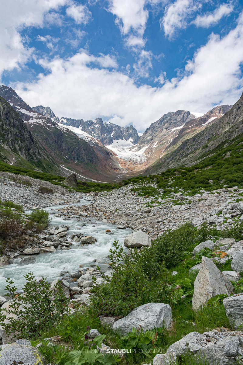 Blick durch das Chelenalptal im Kanton Uri, wo der Chelenreuss zwischen Geröllfeldern und alpiner Vegetation talwärts fliesst, während im Hintergrund der Chelengletscher unterhalb des Winterbergmassivs liegt.