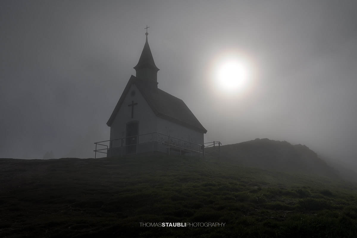 Die Jakobskapelle auf dem Kronberg im diffusen Licht der Sonne, umgeben von dichtem Nebel, der der Szene eine mystische und stille Atmosphäre verleiht.