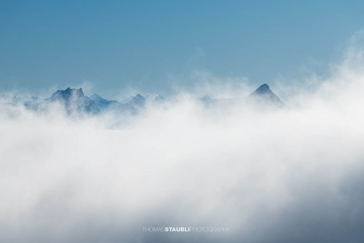 Eine Bergkette ragt im Appenzellerland aus einem dichten Nebelmeer, während Sonnenlicht die Nebelschwaden hochsteigen lässt.