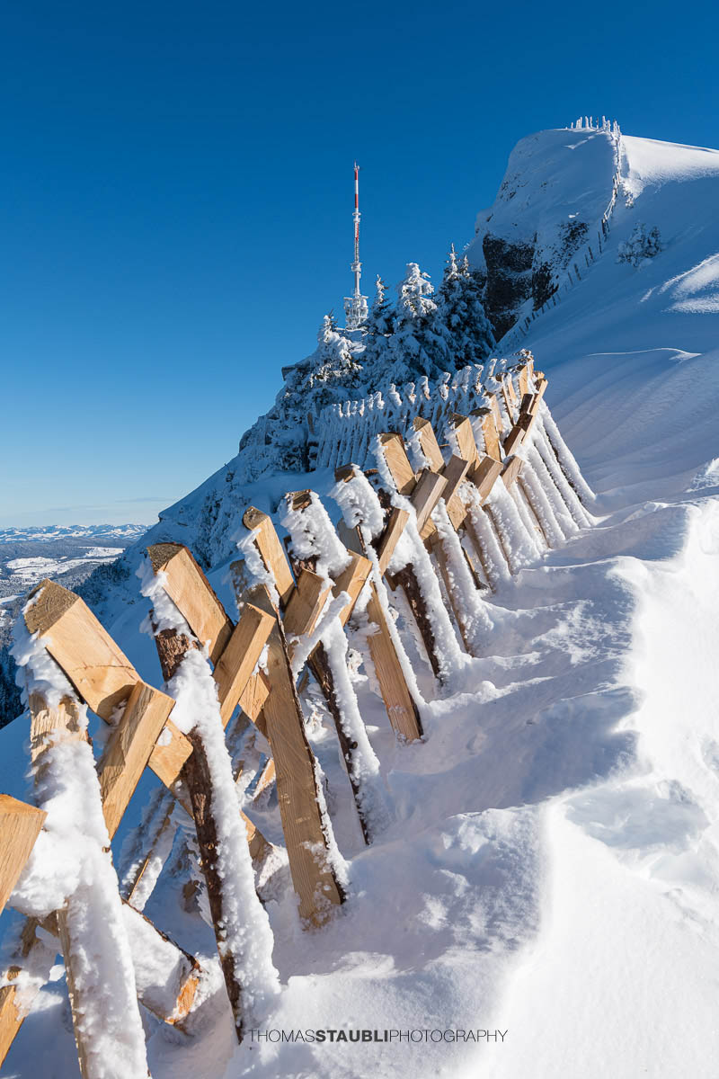 Verschneiter Rigi Kulm mit Schneezäunen, Gipfelantenne und klarem Winterhimmel in der Zentralschweiz.