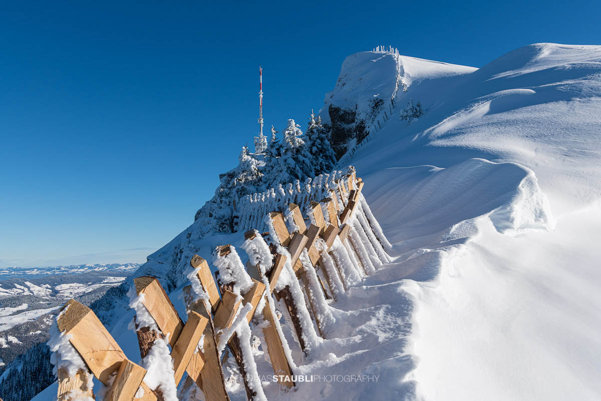 Verschneiter Rigi Kulm mit Schneezäunen, Gipfelantenne und klarem Winterhimmel in der Zentralschweiz.