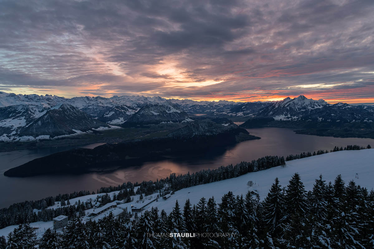 Winterlicher Blick auf den Vierwaldstättersee und den Pilatus im intensiven Abendlicht unter einer dramatisch bewölkten Himmeldecke.