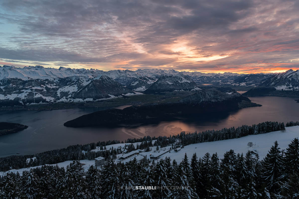 Winterlicher Blick auf den Vierwaldstättersee und den Pilatus im intensiven Abendlicht unter einer dramatisch bewölkten Himmeldecke.