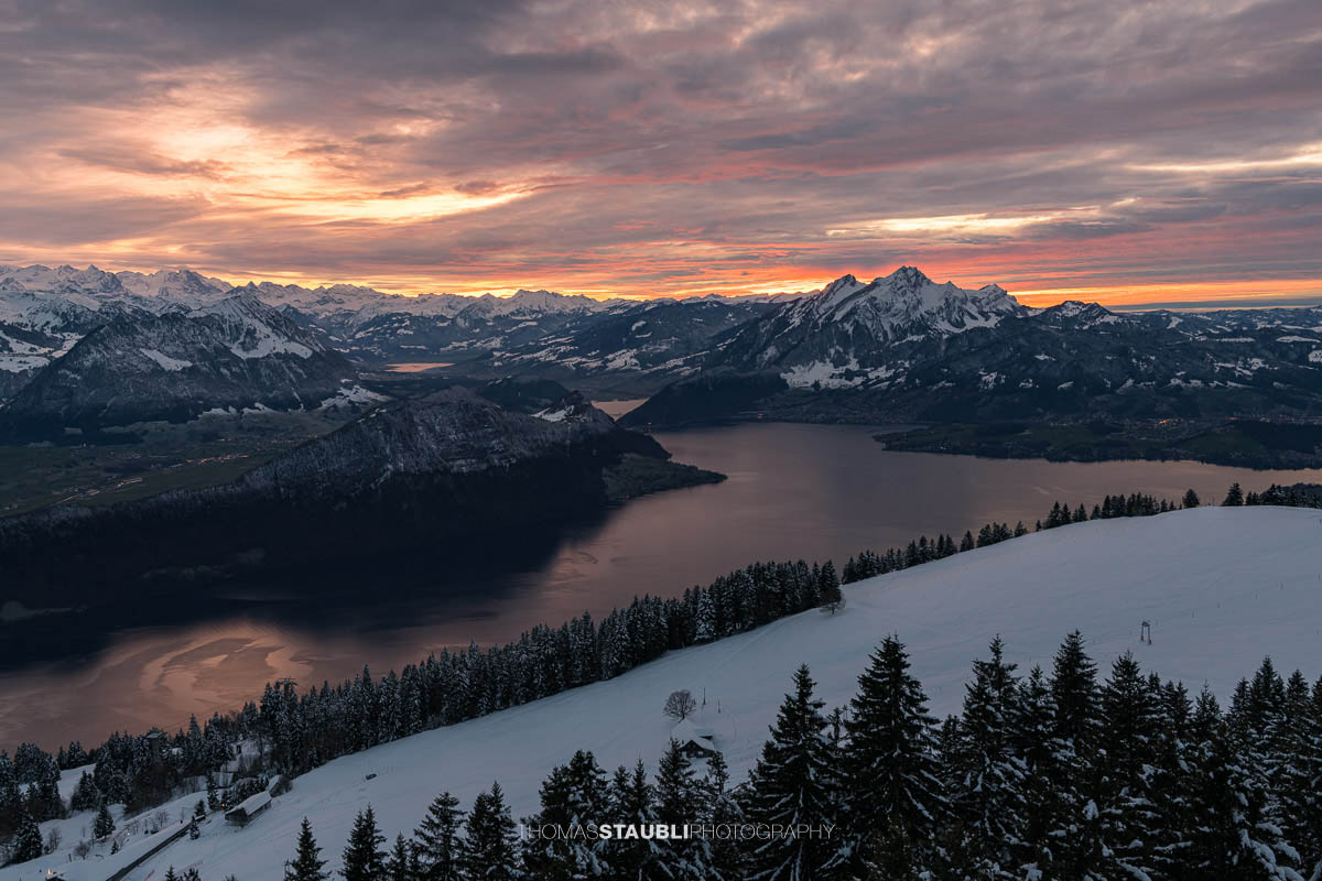 Winterlicher Blick auf den Vierwaldstättersee und den Pilatus im intensiven Abendlicht unter einer dramatisch bewölkten Himmeldecke.