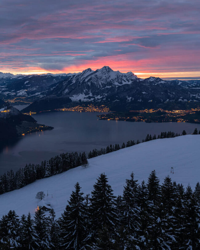 Winterlicher Blick auf den Vierwaldstättersee und den Pilatus im intensiven Abendrot unter einer dramatisch bewölkten Himmeldecke.