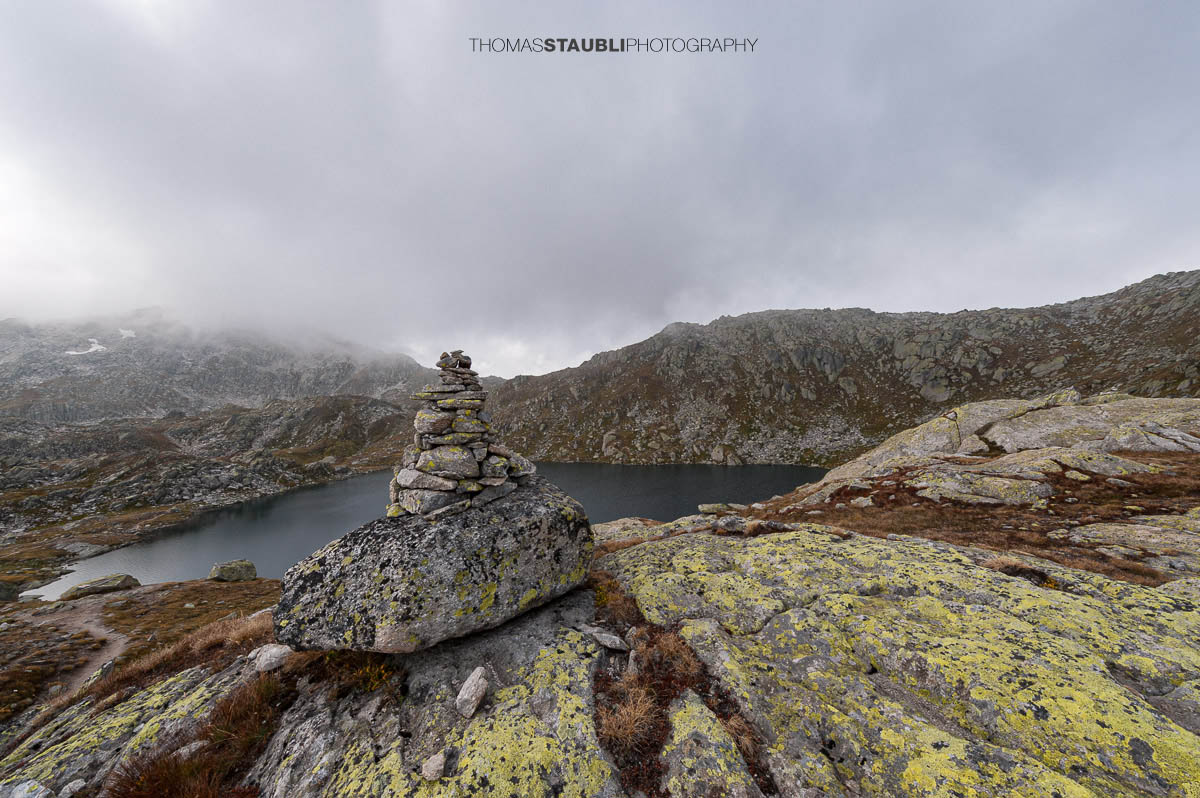 Laghi d’Orsirora nahe dem Gotthardpass, kleiner Hochgebirgssee in karger alpiner Felslandschaft unter wechselndem Himmel.