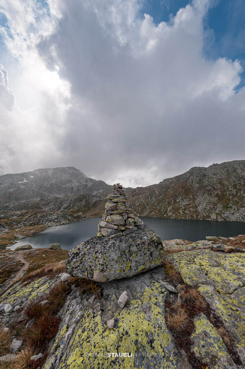 Laghi d’Orsirora nahe dem Gotthardpass, kleiner Hochgebirgssee in karger alpiner Felslandschaft unter wechselndem Himmel.