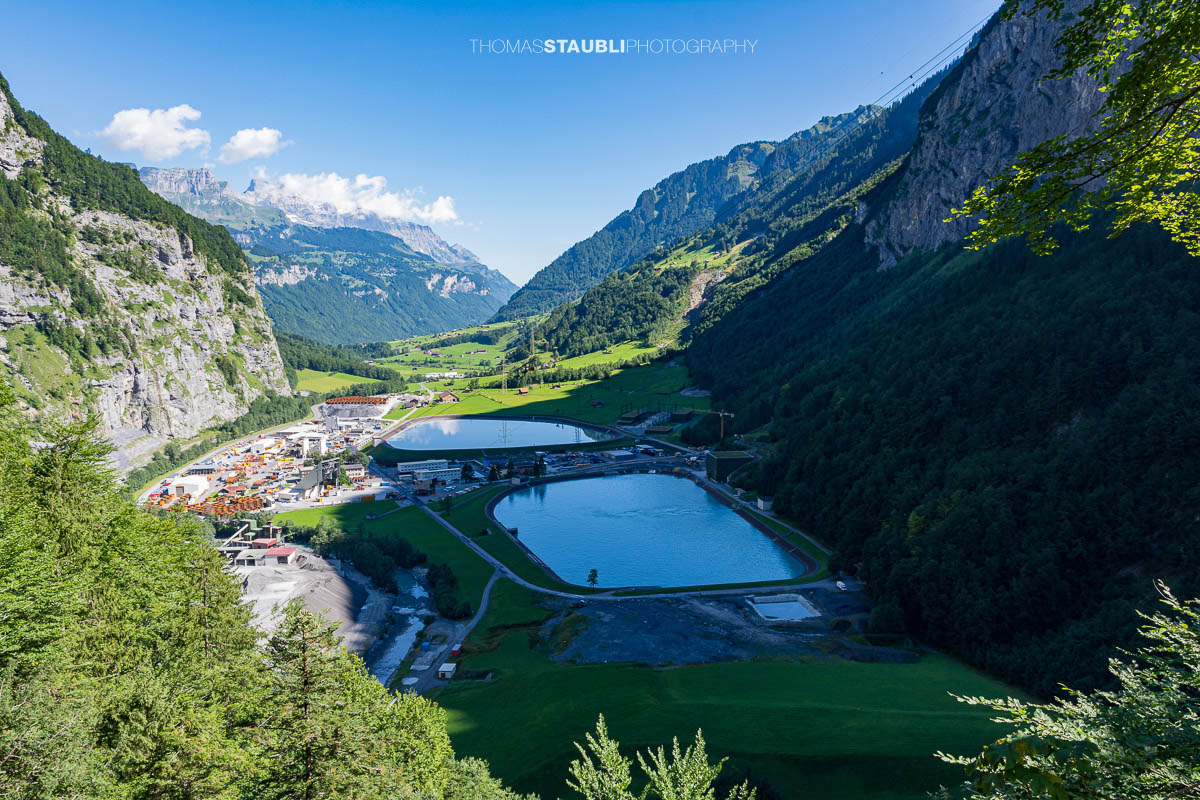 Blick auf Tierfed im Glarnerland mit Industrieanlagen, Speicherbecken und dem grünen Talboden des hinteren Linthtals.