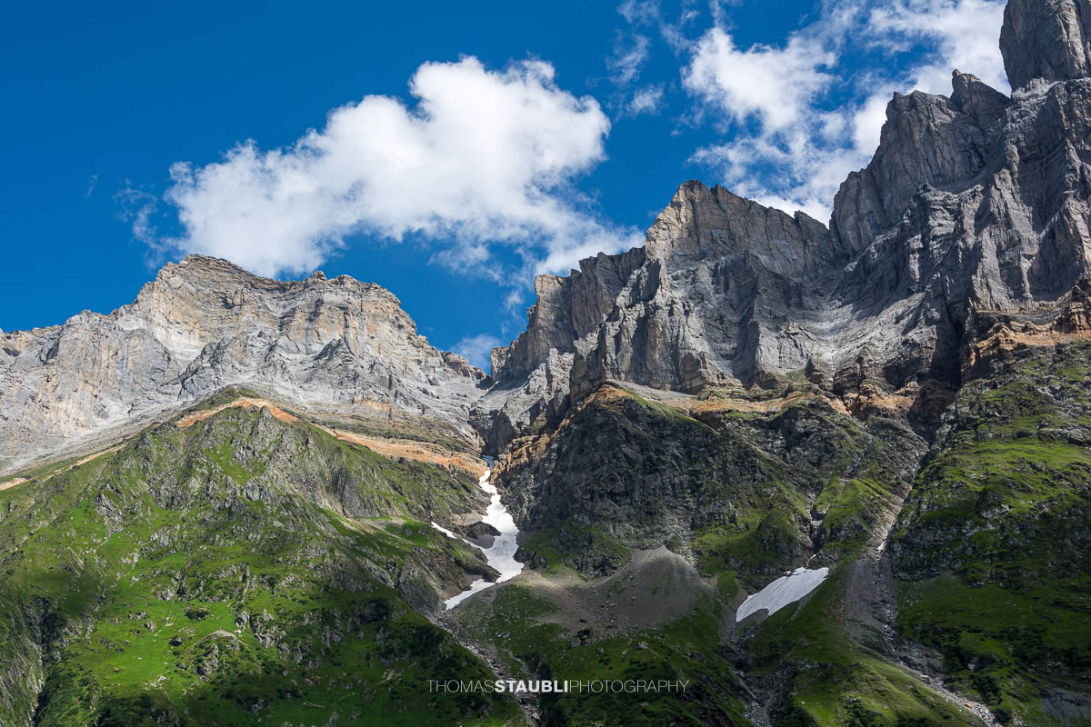 Steile Kalkfelswände von Vorder- und Hinter Schiben im Kanton Glarus, mit grünen Alpflanken und Schneeresten in den Rinnen.