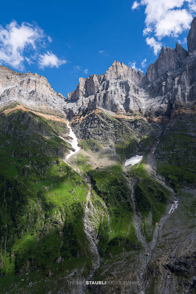 Steile Kalkfelswände von Vorder- und Hinter Schiben im Kanton Glarus, mit grünen Alpflanken und Schneeresten in den Rinnen.