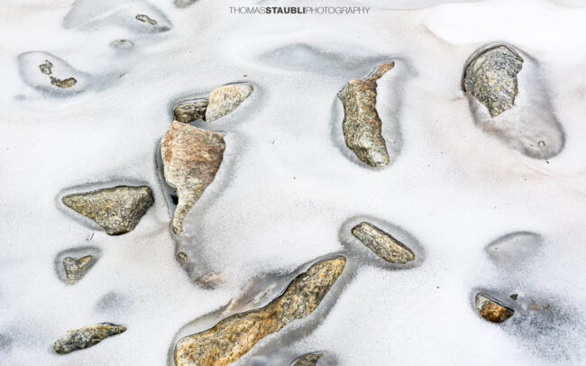 Einzelne Steine die aus dem Schnee ragen