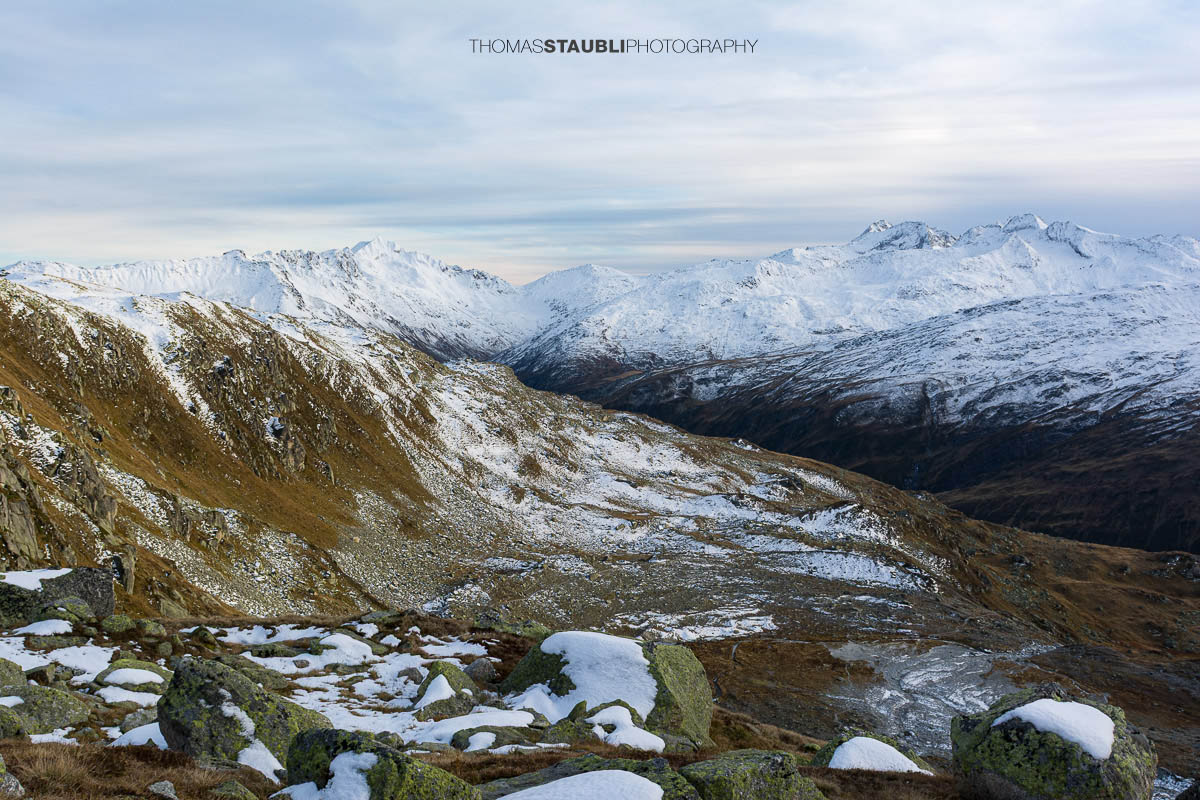 Blick ins Urserental, verschneite Gipfel und herbstlich gefärbte Hänge im Übergang zum Winter.