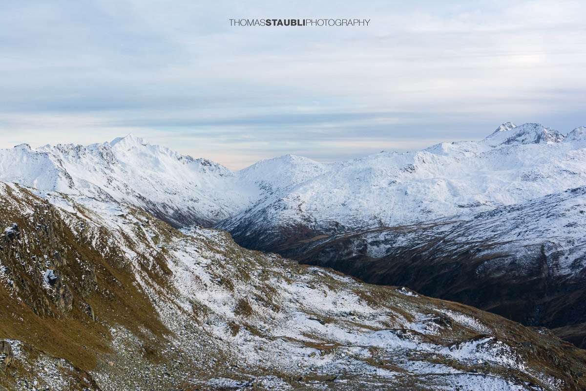 Blick ins Urserental, verschneite Gipfel und herbstlich gefärbte Hänge im Übergang zum Winter.