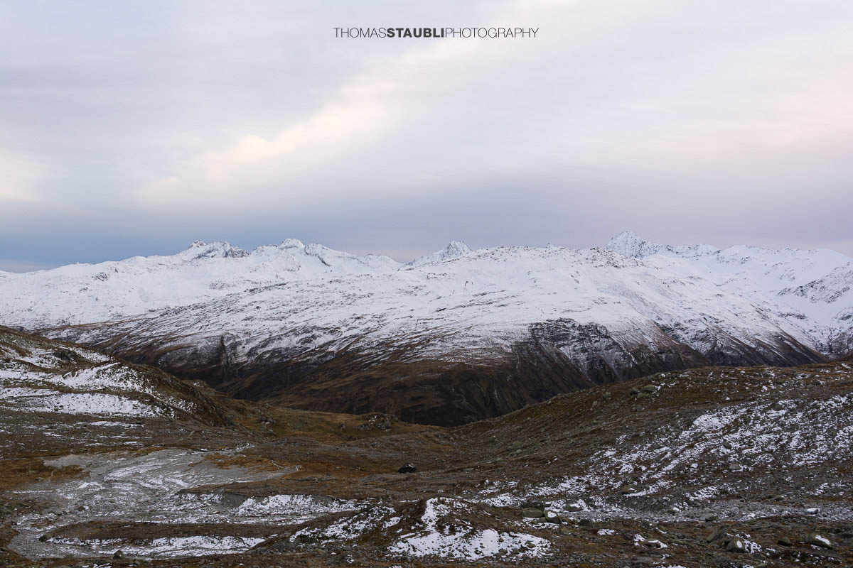 Blick ins Urserental, verschneite Gipfel und herbstlich gefärbte Hänge im Übergang zum Winter.