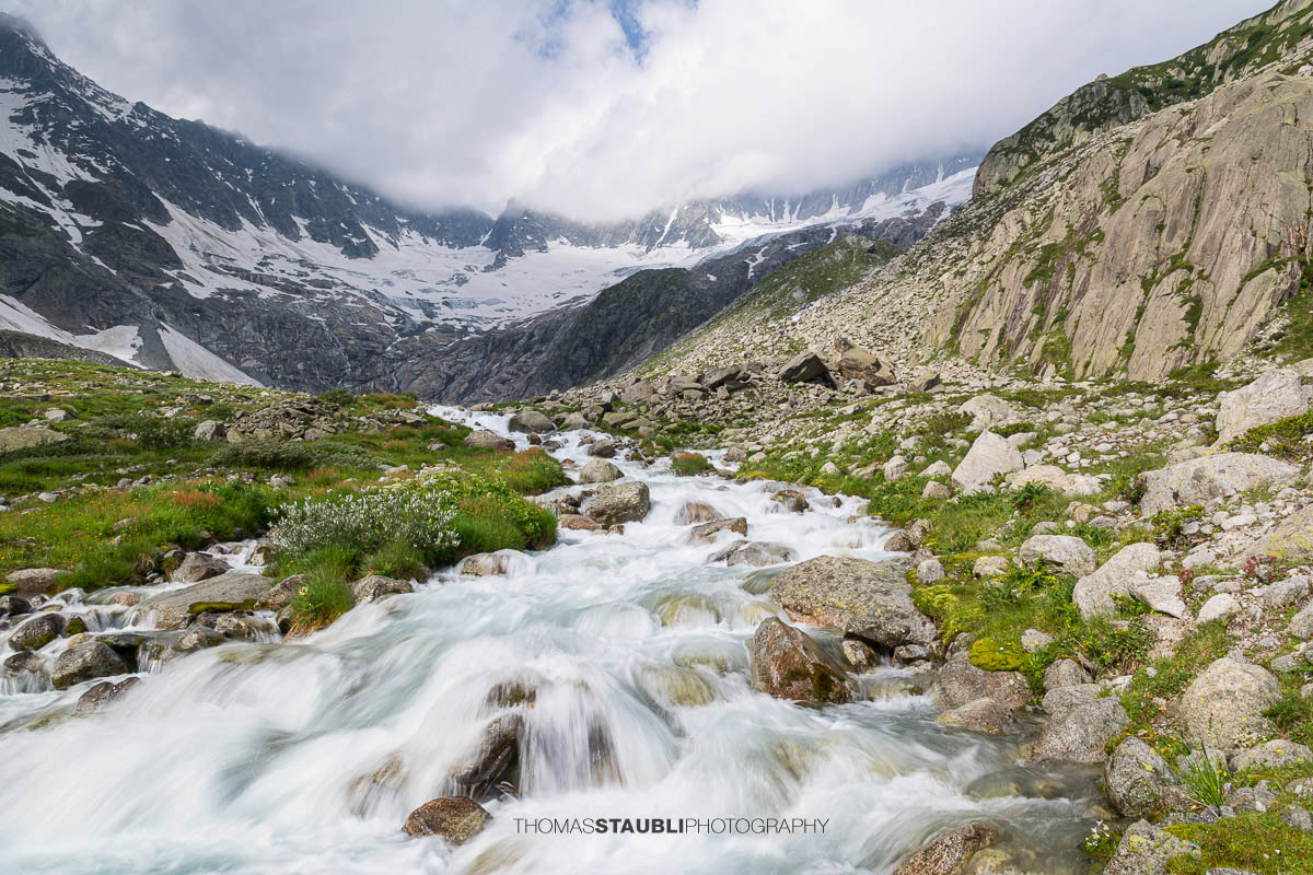 Dammareuss im Göschenertal im Kanton Uri, klarer Gebirgsbach zwischen Felsen und alpiner Vegetation mit Blick Richtung Dammagletscher.