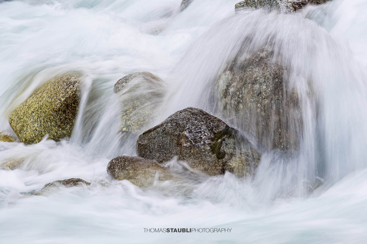 Dammareuss im Göschenertal im Kanton Uri, klarer Gebirgsbach zwischen Felsen und alpiner Vegetation.