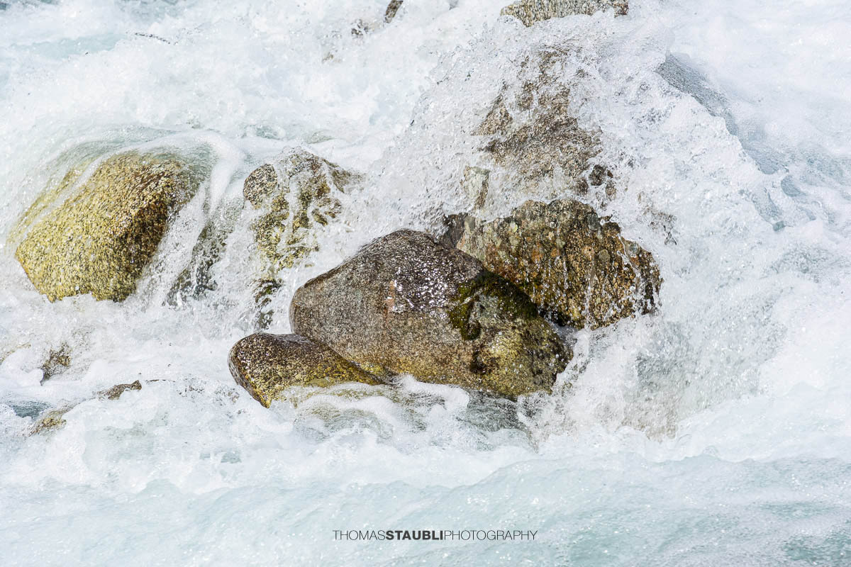 Dammareuss im Göschenertal im Kanton Uri, klarer Gebirgsbach zwischen Felsen und alpiner Vegetation.