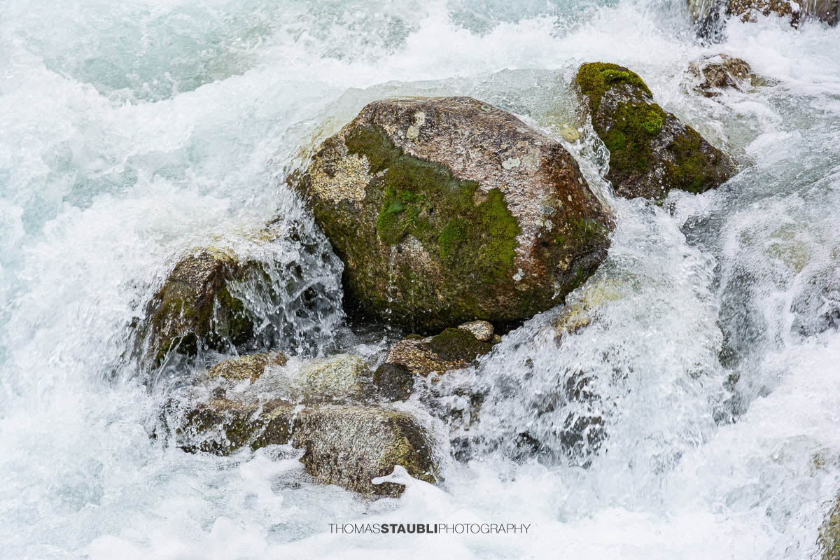 Dammareuss im Göschenertal im Kanton Uri, klarer Gebirgsbach zwischen Felsen und alpiner Vegetation.