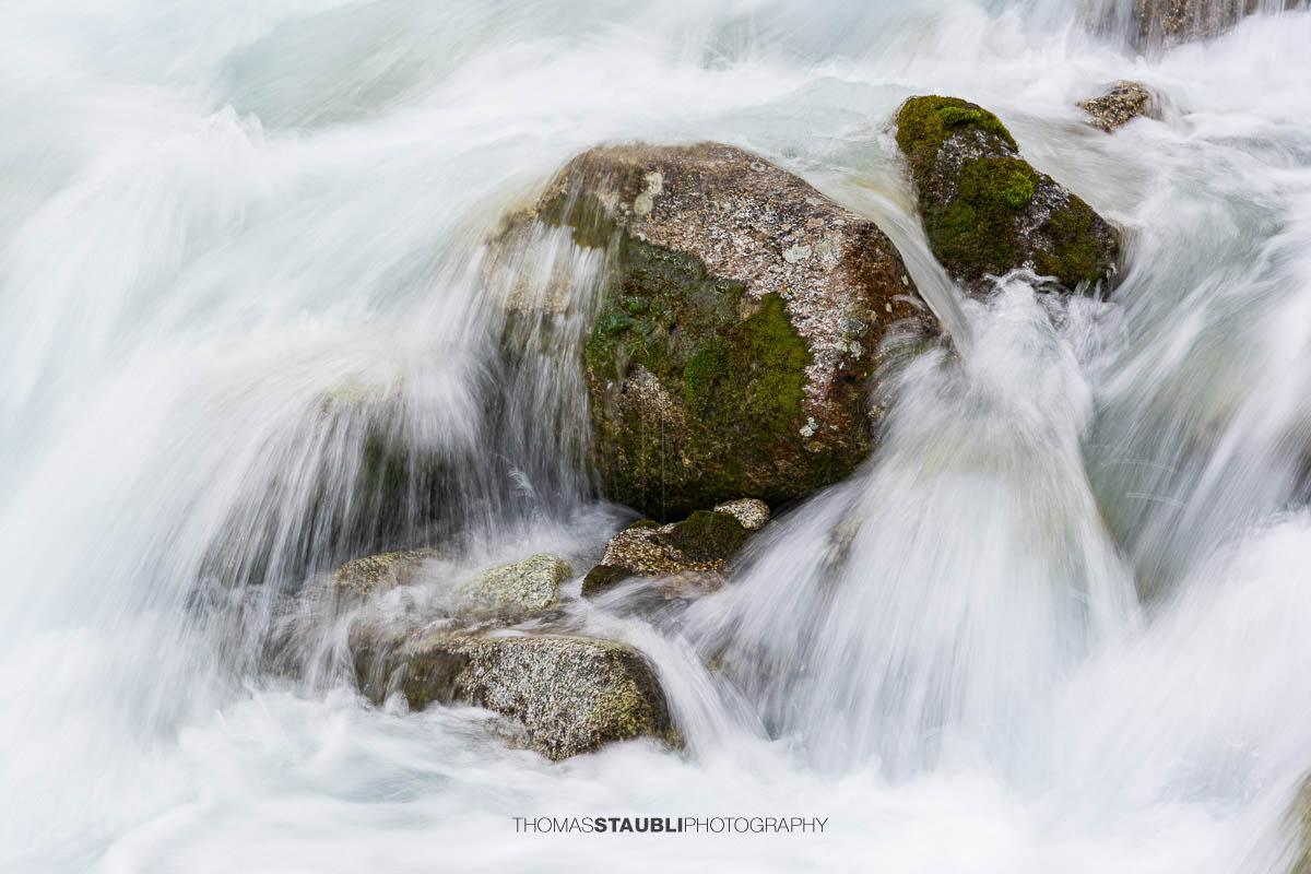 Dammareuss im Göschenertal im Kanton Uri, klarer Gebirgsbach zwischen Felsen und alpiner Vegetation.