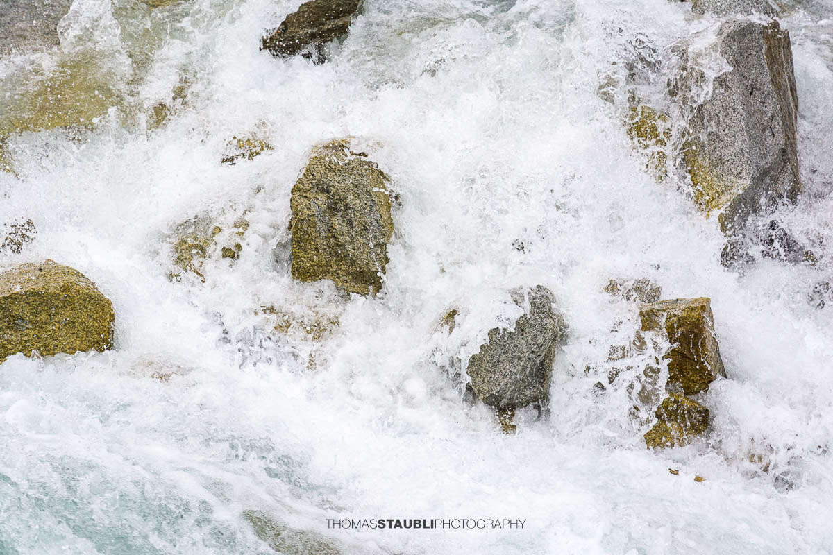 Dammareuss im Göschenertal im Kanton Uri, klarer Gebirgsbach zwischen Felsen und alpiner Vegetation.