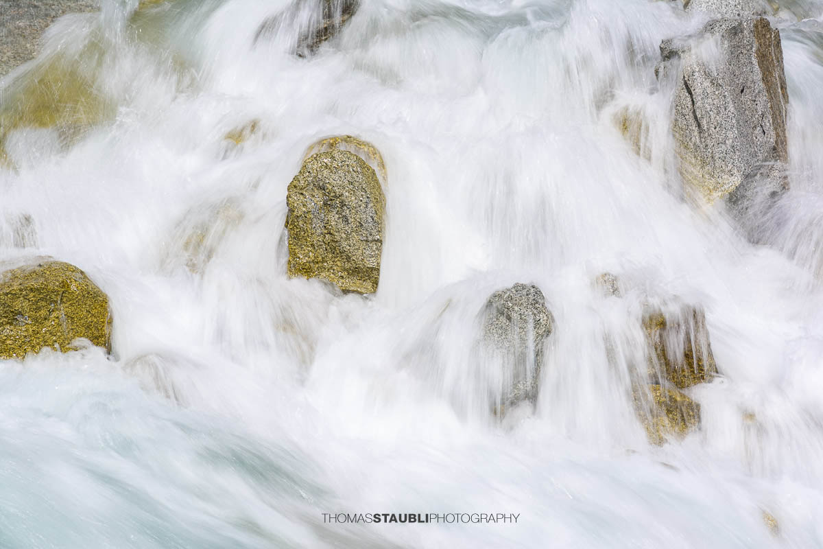 Dammareuss im Göschenertal im Kanton Uri, klarer Gebirgsbach zwischen Felsen und alpiner Vegetation.