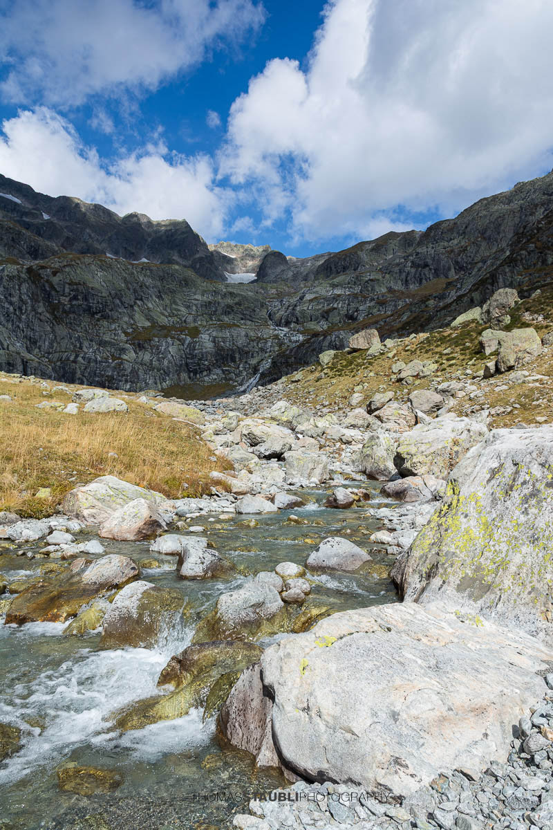 Sustlibach im Meiental in den Schweizer Alpen, klarer Gebirgsbach zwischen Felsen mit steiler Bergkulisse im Hintergrund.