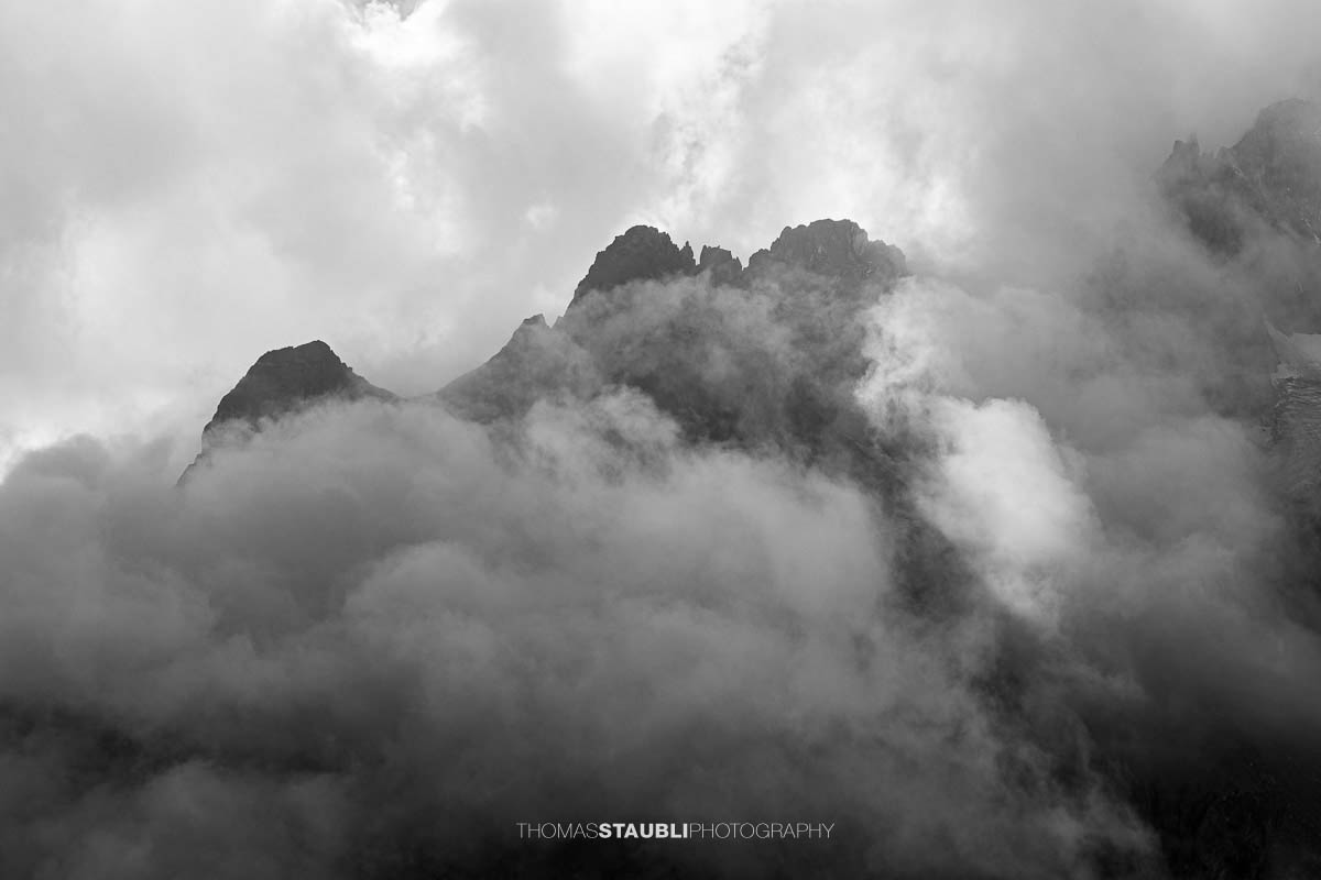 Blick zum Guferstock und Sustenlochspitz in den Urner Alpen, schroffe Berggipfel von dichtem Nebel und Wolken umhüllt.