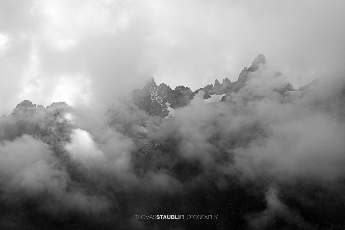 Blick zum Wendenhorn in den Urner Alpen, schroffe Berggipfel von dichtem Nebel und Wolken umhüllt.