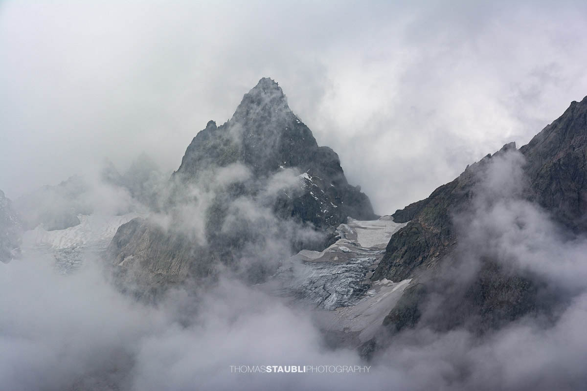 Blick zum Wendenhorn in den Urner Alpen, schroffe Berggipfel von dichtem Nebel und Wolken umhüllt.