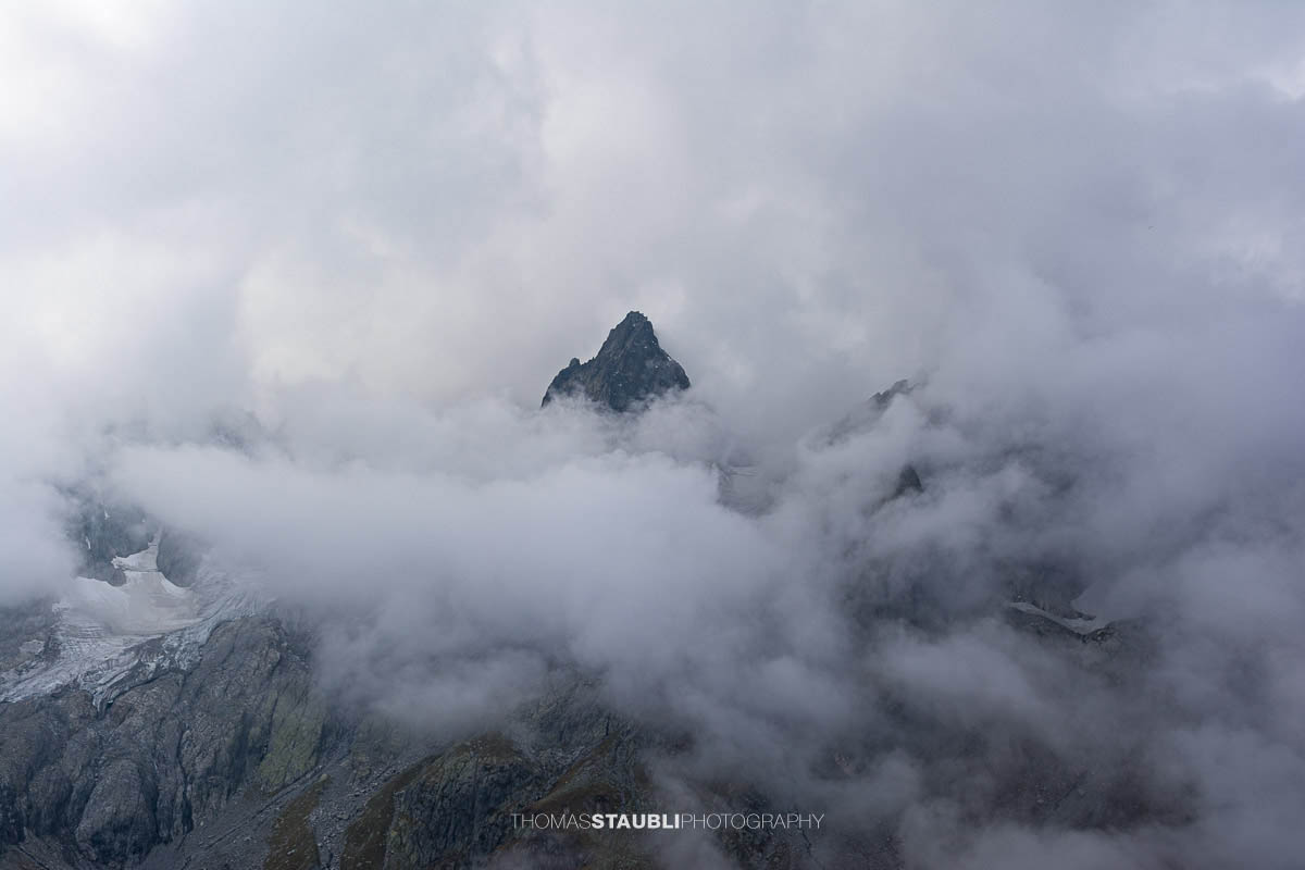 Blick zum Wendenhorn in den Urner Alpen, schroffe Berggipfel von dichtem Nebel und Wolken umhüllt.