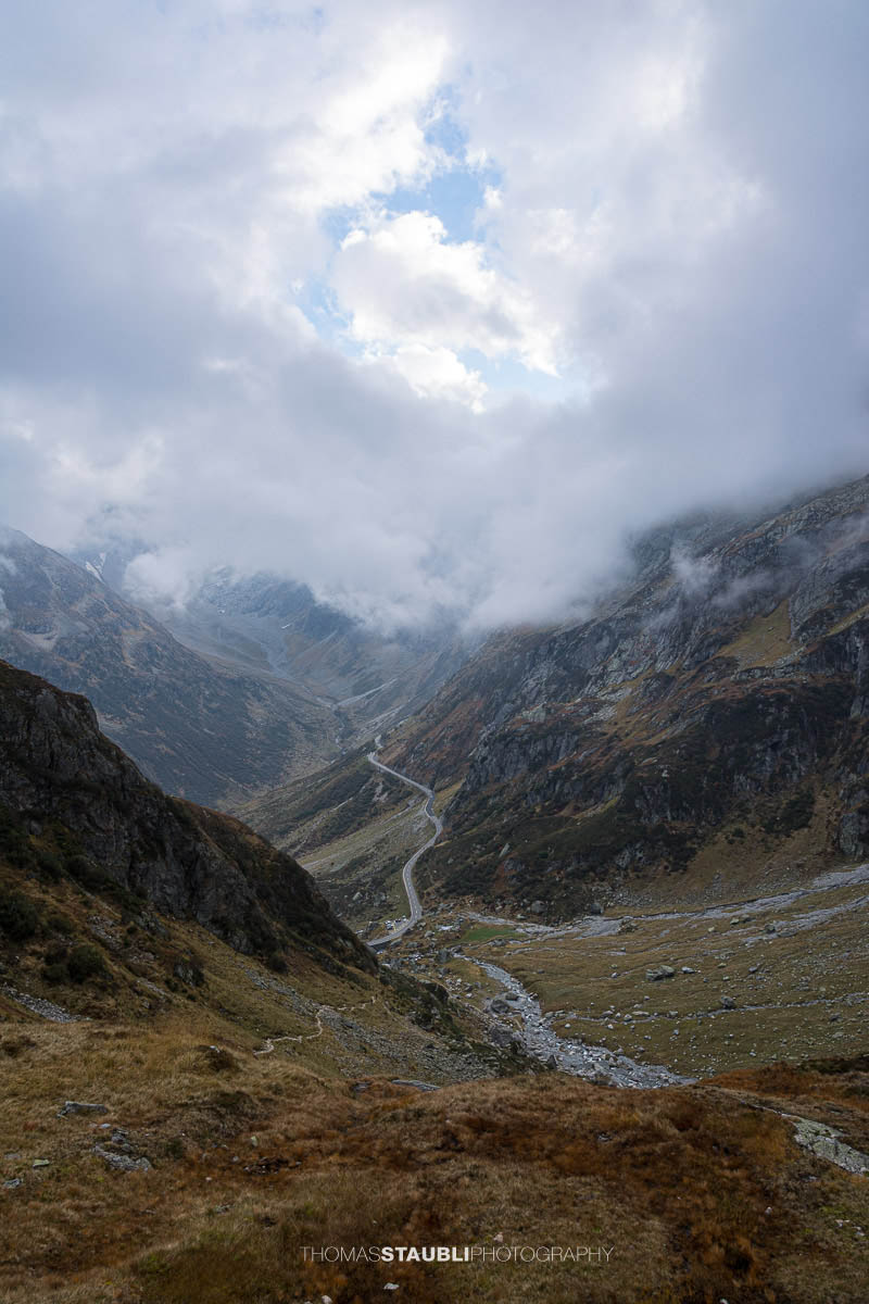 Blick hinunter zur Sustenpassstrasse im Meiental, kurvige Passstrasse zwischen steilen Berghängen und unter tiefhängenden Wolken.