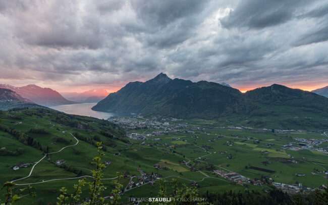 Abendstimmung über dem Talkessel von Schwyz mit Vierwaldstättersee und umliegenden Bergen unter dramatischem Himmel.