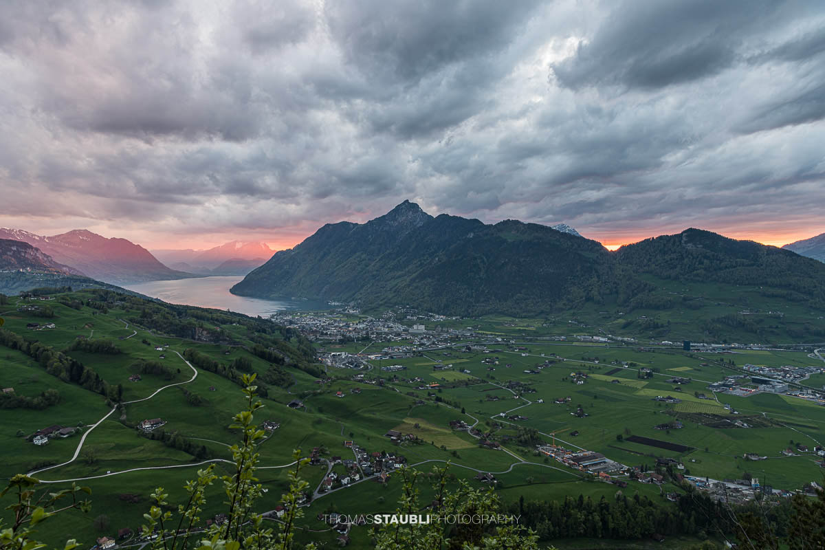 Abendstimmung über dem Talkessel von Schwyz mit Vierwaldstättersee und umliegenden Bergen unter dramatischem Himmel.